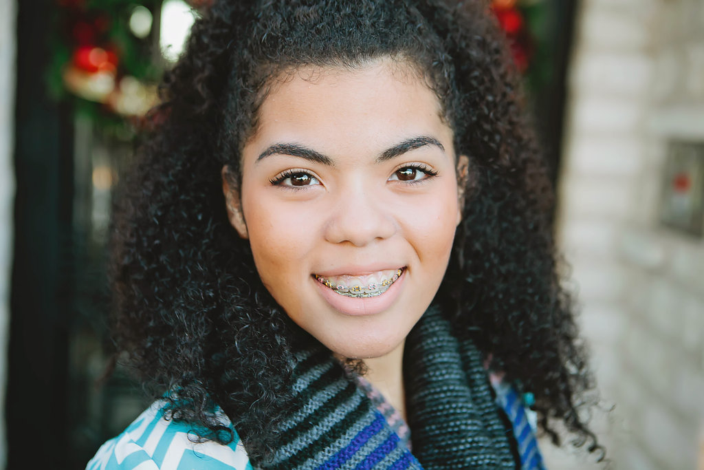Image of teen girl smiling with braces and curly hair | Celebrity Ortho Dentist