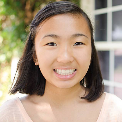 Image of girl smiling in pink top with window behind her | Celebrity Ortho Dentist