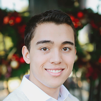 Image of teen boy smiling with blurred red background | Celebrity Ortho Dentist