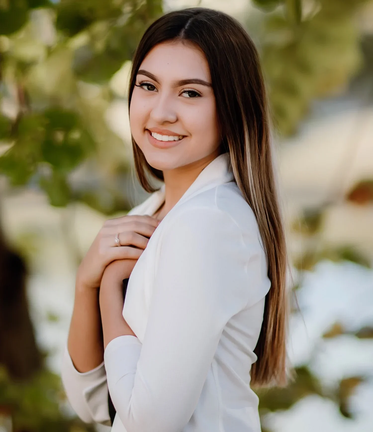 Smiling teen girl wearing white with her hands crossed over her heart | Celebrity Orthodontics
